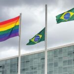 Edifício da CLDF em Brasília com bandeira arco-íris ao fundo, simbolizando anúncio de programa e críticas à negligência LGBTQIAPN+.