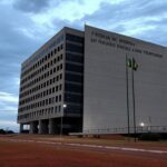 Edifício do TJDFT em Brasília com bandeiras a meio mastro, simbolizando luto pela morte de desembargador.