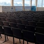 Auditório vazio após conferência sobre segurança pública no Brasil, com palco e cadeiras arrumadas, transmitindo incerteza no impacto real.