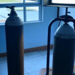 Cilindro de oxigênio e conta de energia em residência no DF, simbolizando falhas no apoio a pacientes crônicos.