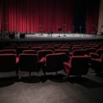 Teatro brasileiro com palco preparado para estreia de musical, representando transição de carreira com dúvidas.