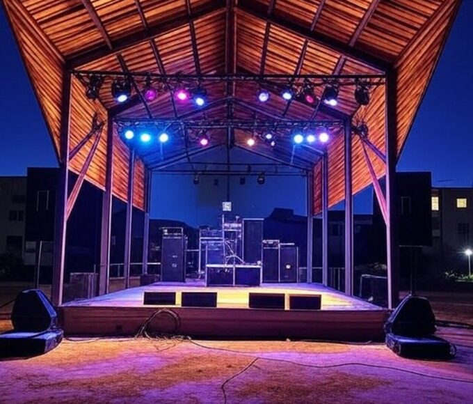 Palco de evento musical Quinta do Pop e Rock em Águas Claras, com equipamentos de som e luzes, representando estreia na cena musical brasileira.