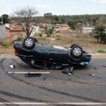 Carro Ônix capotado em acidente na QR 125, Samambaia Sul, DF, com destroços na rua urbana.