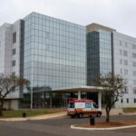 Exterior de hospital em Brasília com ambulância na entrada, representando internação por broncopneumonia bacteriana.