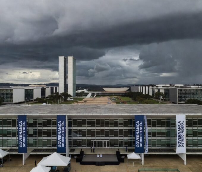 Fachada da Câmara Legislativa do DF sob nuvens escuras, expondo falhas na governança de Brasília.