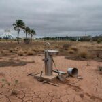Ponto de hidratação isolado em praça de Brasília com solo seco, destacando insuficiência contra a seca.