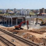 Obras de expansão da Linha 1 do Metrô-DF em Samambaia, com trilhos e máquinas de construção em ambiente urbano brasileiro.