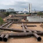 Obras de abastecimento de água no DF com tubulações em terreno seco, destacando risco de escassez hídrica.