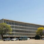 Fachada do Fórum de Planaltina com viaturas policiais, representando interrogatório em caso de chacina familiar.