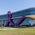 Edifício da Sejus-DF em Brasília com símbolo contra violência doméstica, representando ampliação de programas para 1,5 mil trabalhadores.