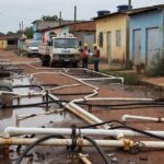 Ligações clandestinas de água em rua de Sucupira, DF, com tubulações expostas e poças contaminadas, agravando riscos à saúde.