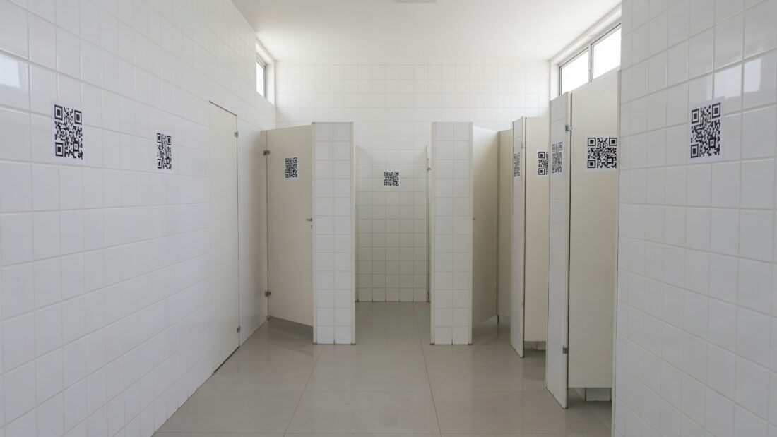 Adesivos com QR Code em banheiro público do DF divulgando o programa Direito Delas