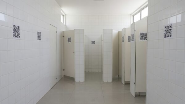 Adesivos com QR Code em banheiro público do DF divulgando o programa Direito Delas