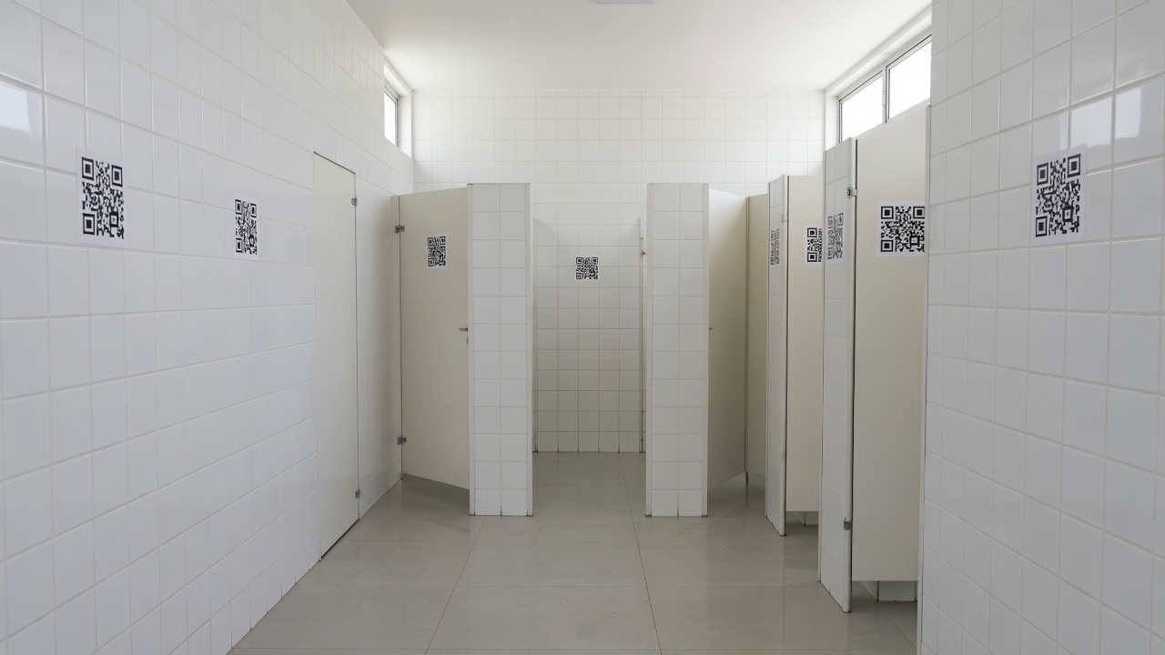 Adesivos com QR Code em banheiro público do DF divulgando o programa Direito Delas