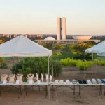 Feira de saúde no DF com tendas e equipamentos ortopédicos, skyline de Brasília ao fundo