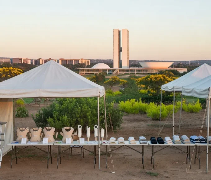 Feira de saúde no DF com tendas e equipamentos ortopédicos, skyline de Brasília ao fundo